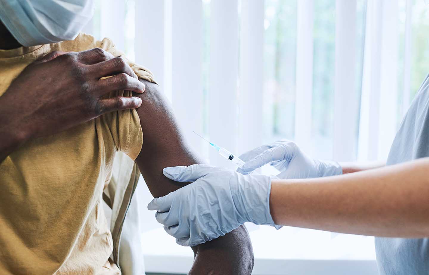 A black man receives a vaccine from a doctor