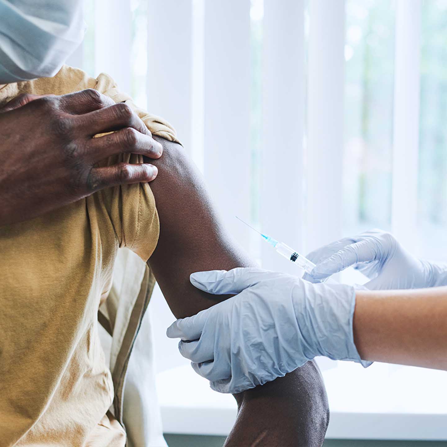 A black man receives a vaccine from a doctor