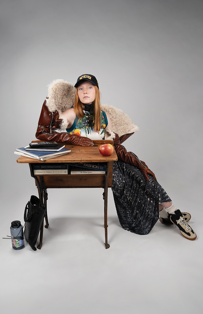 model wearing vintage clothes and sitting at a school desk