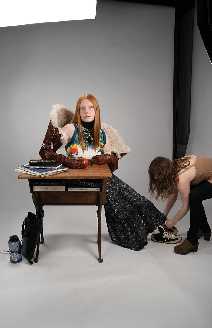 model wearing vintage clothes and sitting at a school desk