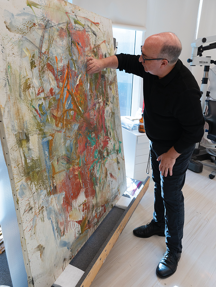 Scott Nolley cleans Joan Mitchell’s 1962 painting, “Giboulee (Sudden Shower),” with a long Q-Tip-shaped tool