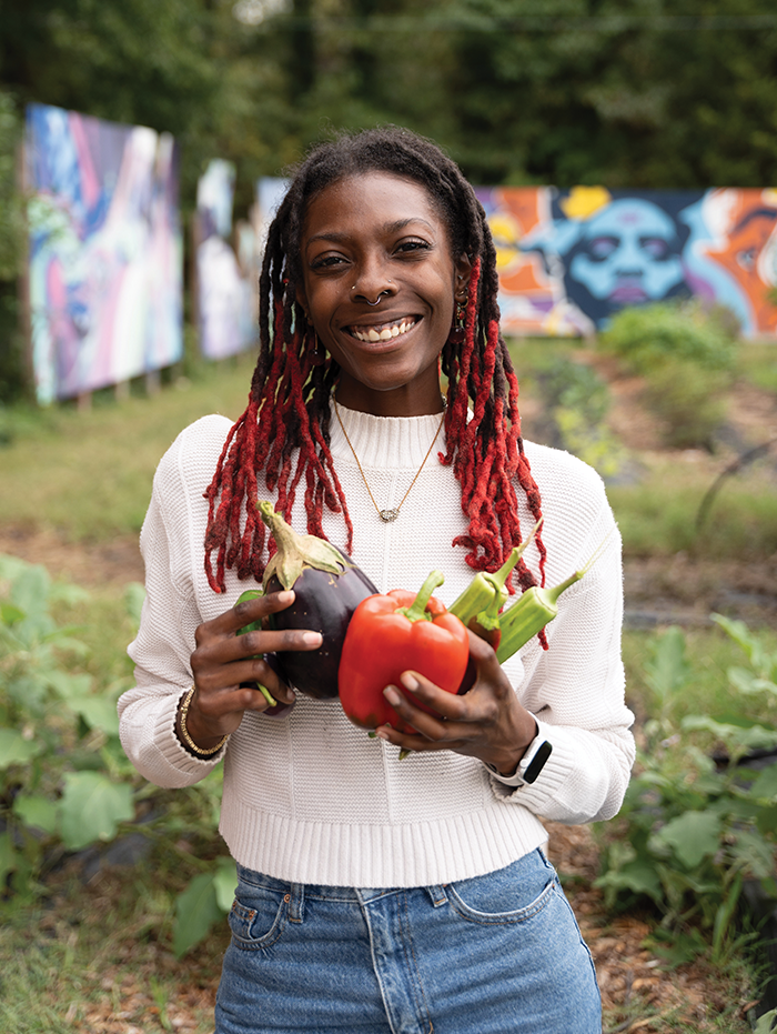 Taylor Scott standing in a garden and holding vegetables