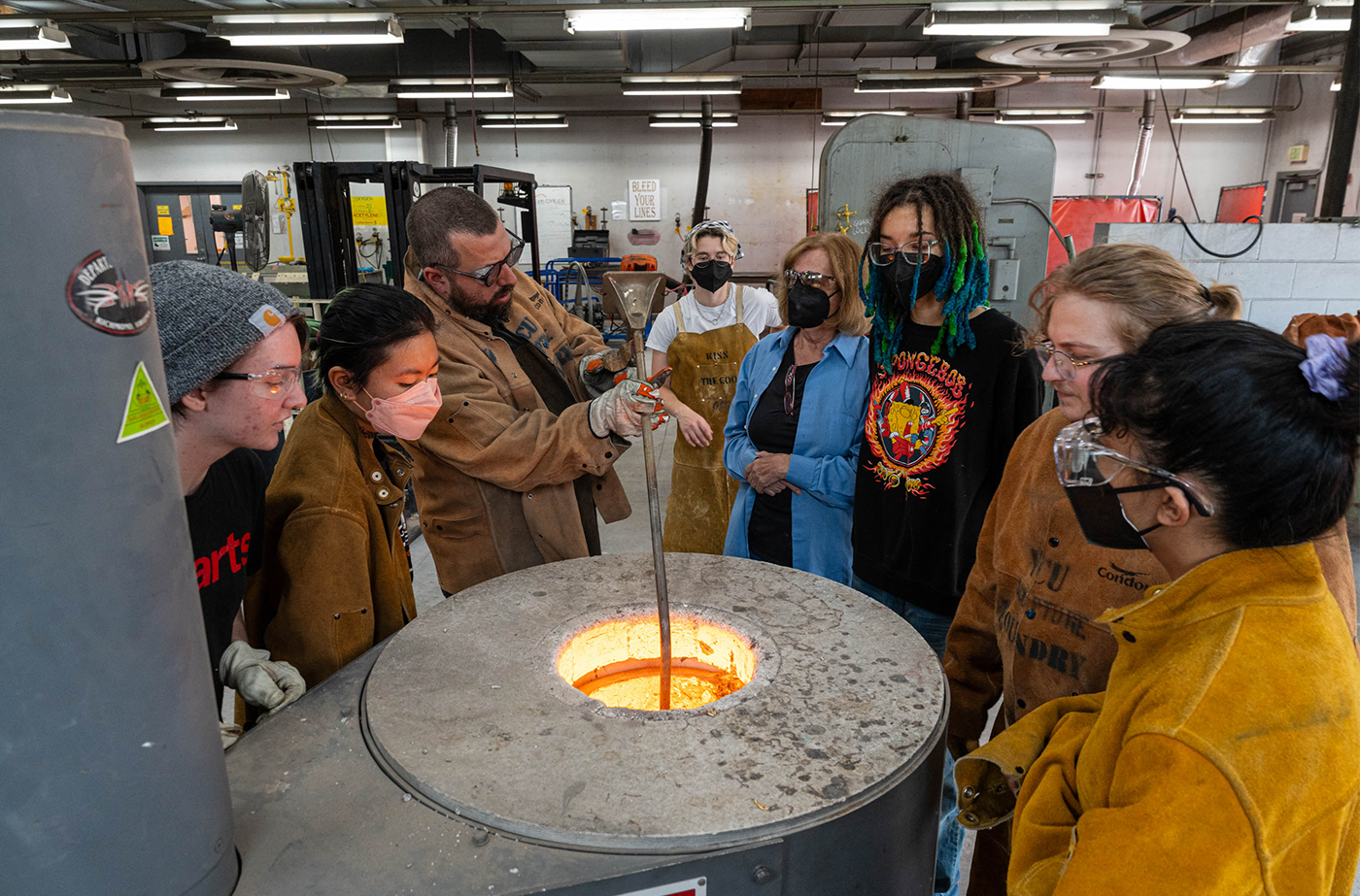 Jesse Burrowes, an adjunct instructor in the Department of Sculpture + Extended Media in the School of the Arts, checks the temperature of the molten bronze.