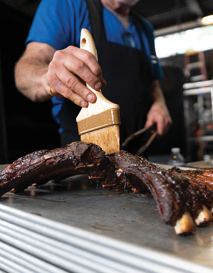 Buz brushes racks of baby back ribs with an emulsion